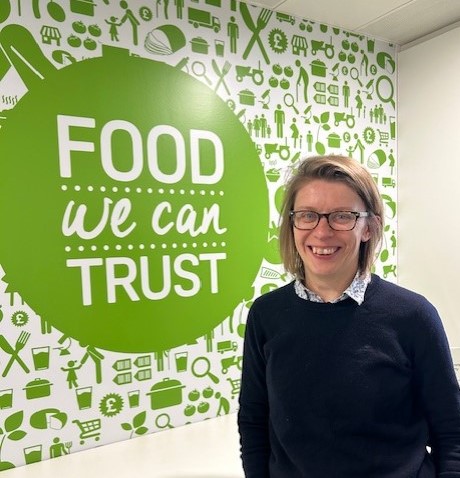 Ruth Nolan, Director of People & Resources in front of a large green sign 'Food we can Trust'